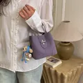 Purple suede bucket bag with silver twist lock and cute knitted bear charm accessory - Purple