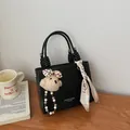 Minimalistische schwarze Handtasche mit Plüschbär-Anhänger und Blumenschal-Detail - Mit Anhänger / Schwarz