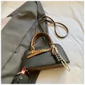 Detail of minimalist black leather crossbody bag with brown handle and cocoa charm deco - With Pendant / Black
