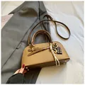 Macro detail of khaki Boston bag with decorative charms and metal bottom studs - With Pendant / Brown