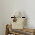 Elegante bolso de mano tipo cubo en cuero suave beige con colgante de madera - Albaricoque Crema