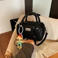 Zwarte leren crossbodytas met zilveren logo en een mintgroene poppenhanger - Zwart (Met Hanger)