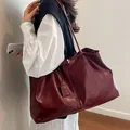 Large burgundy tote bag with glossy finish and long shoulder straps worn by a model - Burgundy