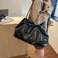 Large black oil wax leather tote bag with glossy texture shown in office setting - Black