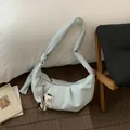 Light blue crescent handbag with pleated details and white horse charm on wood floor - With Pendant / Blue