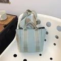 Light green canvas bucket bag with contrast color shoulder strap and top handles - Blue