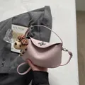 Light pink leather dumpling handbag with silver twist lock and plush puppy charm - Pink With Pendant