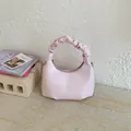 Detail of light pink shoulder bag featuring a ruched cloud handle and fashion logo - Pink