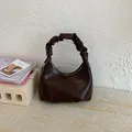 Detail of dark brown pleated hobo bag with scrunchie handle and polished leather texture - Brown