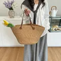 Handgewebte Strohtasche mit braunen Ledergriffen und geräumigem Innenraum am Modell - Khaki