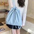 Light blue drawstring backpack worn on back in a minimalist aesthetic cafe setting - Blue