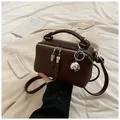 Detail of a brown leather box bag featuring silver T-shaped dual zippers and a ball charm - Black