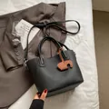 Black litchi grain shoulder bag with top handle and brown elephant charm detail - Black