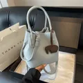 Light blue lychee pattern bucket bag with leather elephant charm on a leather sofa - Blue