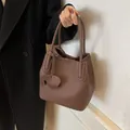 Caramel brown lychee leather bucket bag with a decorative elephant charm and dual handles - Coffee