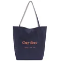 Detail of navy blue canvas tote bag featuring orange text print and checkered strap - Navy Blue