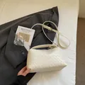 Detailansicht der cremefarbenen geflochtenen Ledertasche mit Blazer und Kunstbuch - Gebrochenes Weiß