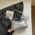 Détail d'un sac à main tressé argenté avec une texture lisse et une bandoulière - Argent