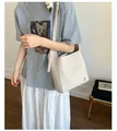 Détail du sac seau en cuir crème avec logo argenté et bandoulière réglable - Blanc