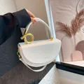 Chic white leather saddle bag featuring a gold knot metal clasp and a slim shoulder strap - White