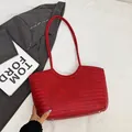 Red woven leather tote bag with silver protective feet shown on white bedding - Red