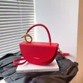 Chic red semi-circle leather handbag with gold knot handle on a minimalist background - Red
