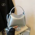 Sac seau argenté avec texture litchi et poignée supérieure sur une valise - Argent