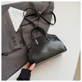 Sac à main noir brillant forme coquillage avec bandoulière sur tenue de bureau - Noir (Brillant)