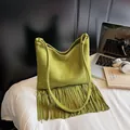 Green suede tote bag with fringe details on a minimalist desk with office accessories - Green