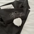Mini silver heart-shaped mirror bag with metallic ball chain on black blazer - Apple Silver