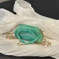 Emerald green marble acrylic clutch with gold chain strap on white satin background - Green