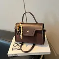 Deep brown baguette bag with beaded charms and adjustable strap on a white book base - Brown with Pendant
