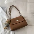 Brown leather crossbody bag with silver buckle and plush charm on white fabric - With Pendant / Brown