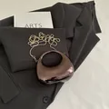 Pochette demi-lune marron foncé métallisé avec chaîne à perles dorées sur un blazer - Marron