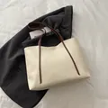 Minimalistische cremeweiße Tote Bag mit braunen Schultergurten auf einem schwarzen Blazer - Weiß