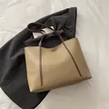 Minimalistische khakifarbene große Tragetasche mit braunen Trägern auf weißem Grund - Khaki