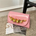 Pochette en cuir verni rose avec détail en métal doré ondulé et bandoulière - Rose