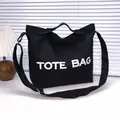 Large black canvas tote bag with white TOTE BAG print and adjustable shoulder strap - Black