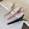 Three matte hair clips in black, beige and pink placed on a decorative ceramic plate - Pink and Cream White