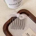 Elegant pearl white bow hair comb with metallic teeth on a rustic wooden tray - Mermaid Pearl Bow Hair Comb