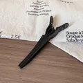 Matte black long hair clip for root volume and styling on wooden tabletop - Black