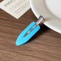 Light blue acetate waterdrop hair clip with silver metal grip on a wooden surface - Blue