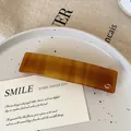 Elegant amber tortoise shell acetate hair clip with silver logo on ceramic tray - Milk Coffee