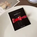 Barrette nœud en résine rouge translucide présentée sur une carte de bijoux de luxe - Rouge