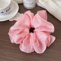Elegant light pink organza scrunchie with soft ruffled edge on dark wooden background - Pink