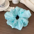 Light blue oversized scrunchie with sheer organza fabric on a dark wood background - Aqua