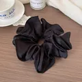 Elegant large black satin scrunchie with thick pleats and glossy finish on wooden background - Black