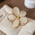 Floral hair claw clip with gold metal edges and white enamel petals on a beige bag - Cream White Flower Claw