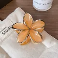 Elegant gold-edged frangipani hair claw with orange resin petals and alloy frame - Orange