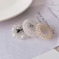 Three spiral telephone cord hair ties with pearls, glitter, and gold beads on a ceramic plate - Multicolor